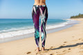 Person wearing colorful leggings on a beach with ocean and sky in the background