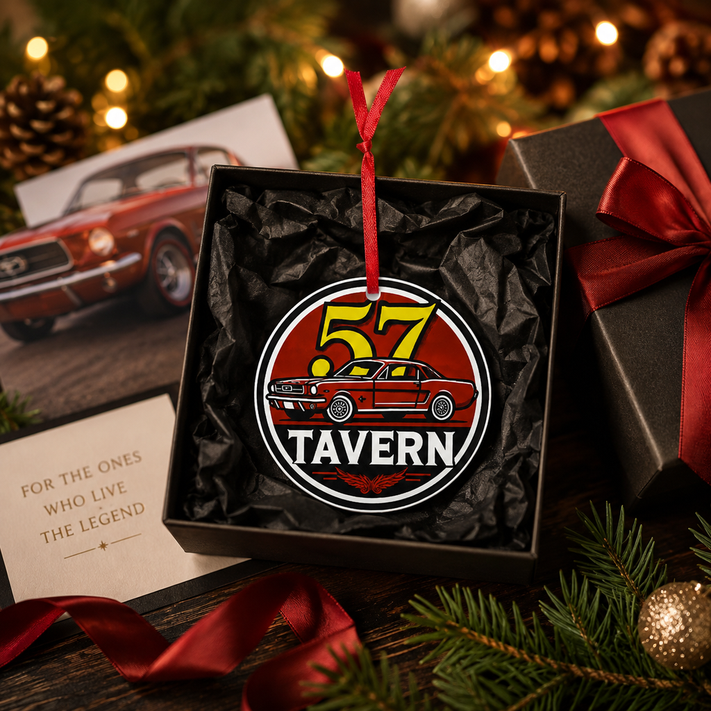 A circular metal ornament featuring a red classic car and the text '57 TAVERN' hangs from a red ribbon inside an open black gift box. The box is styled with holiday greenery, warm string lights, a red ribbon, and a vintage car photo card.