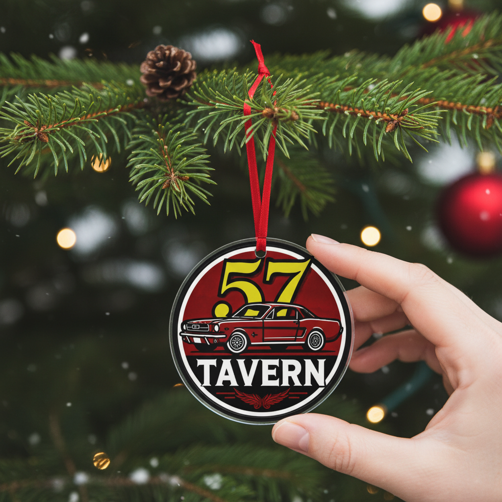 A hand holds a round Christmas ornament featuring a red car and the words “57 TAVERN,” hanging in front of a decorated Christmas tree with pine branches and warm lights.