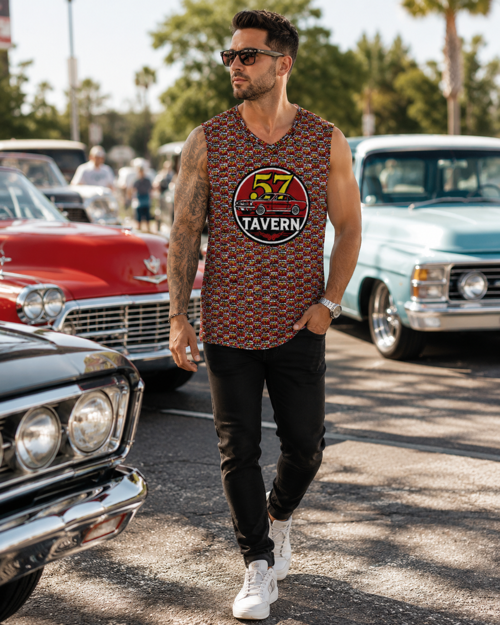 A man wearing a sleeveless patterned tank top with a '57 Tavern' graphic, black pants, and white sneakers, walking outdoors between classic cars.