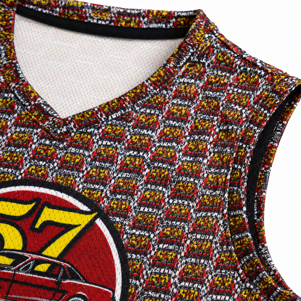 Close-up of a sleeveless V-neck basketball jersey with an all-over repeating red, yellow, black, and white pattern, plus a large circular car graphic in red, yellow, black, and white on the lower left.
