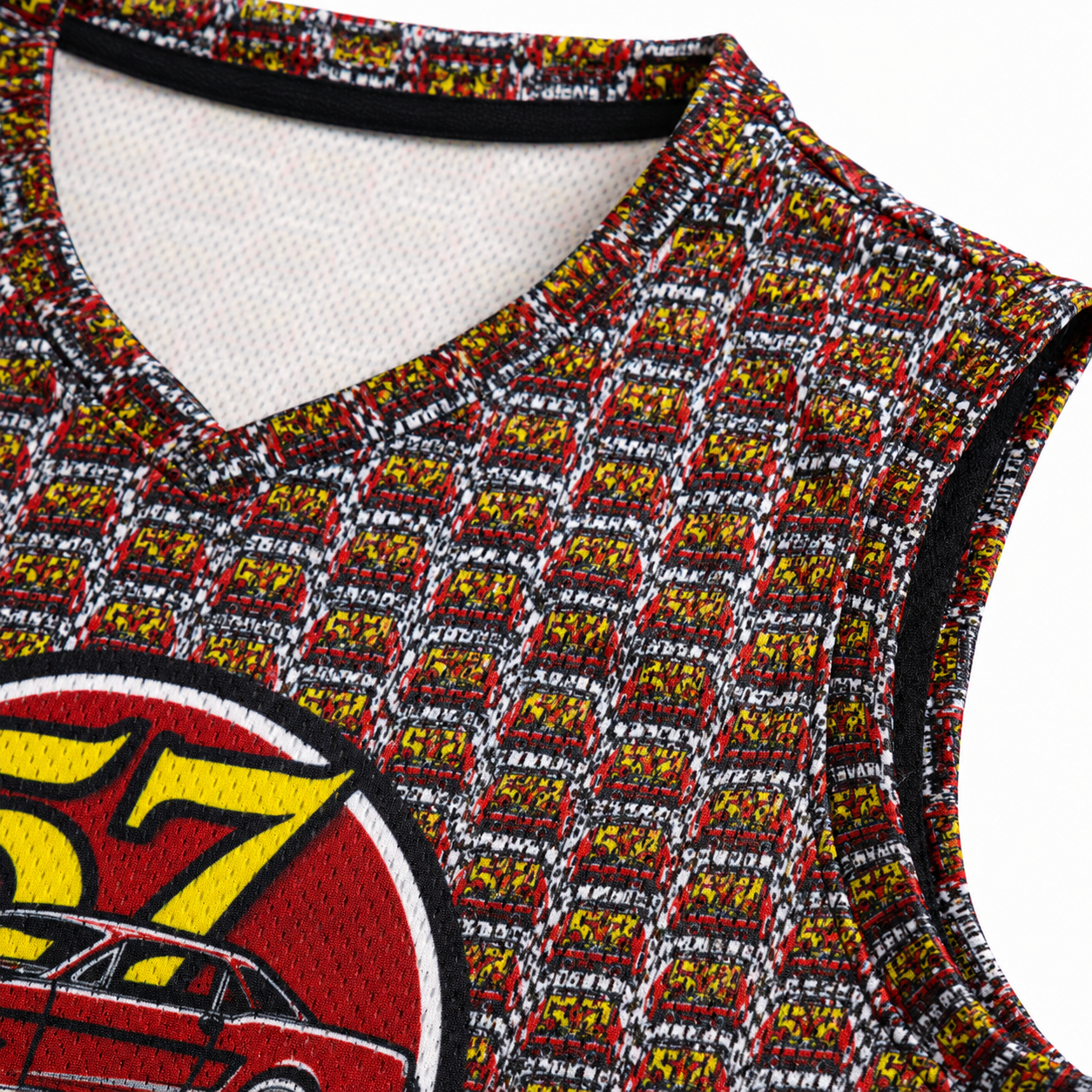 Close-up of a sleeveless V-neck basketball jersey with an all-over repeating red, yellow, black, and white pattern, plus a large circular car graphic in red, yellow, black, and white on the lower left.