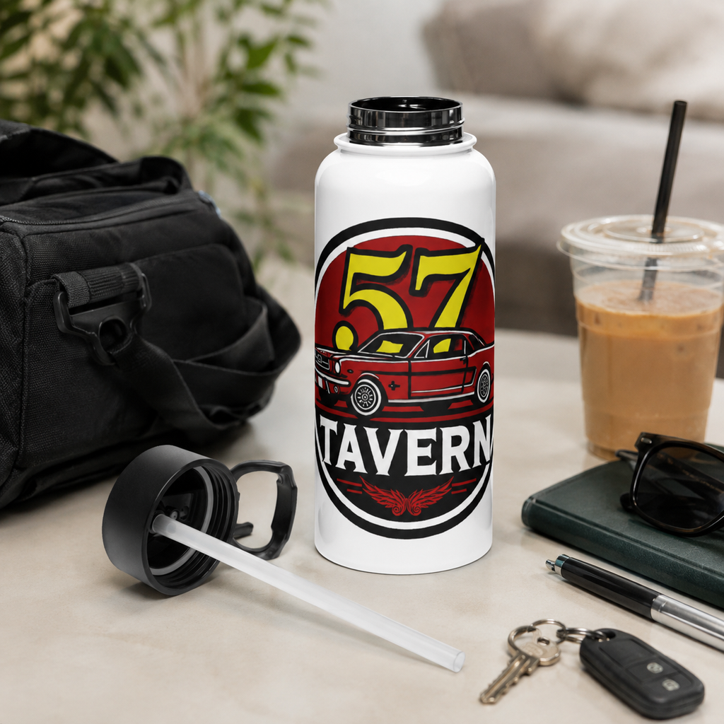 A white insulated water bottle with a black lid stands on a tabletop in a styled indoor setting. The bottle has a large circular graphic reading “57 TAVERN” with a red car illustration.