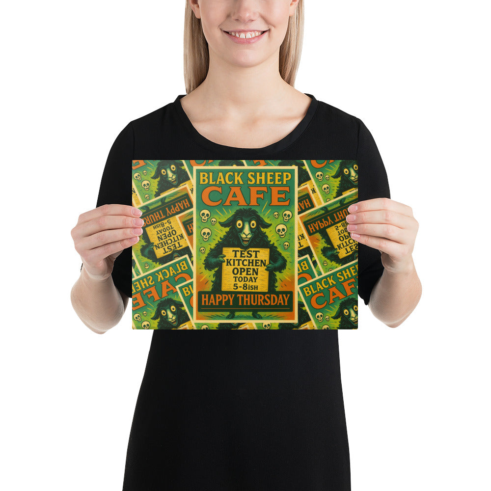 A woman holding a rectangular art print featuring a vintage-style 'Black Sheep Cafe' poster design with green, yellow, and orange tones.