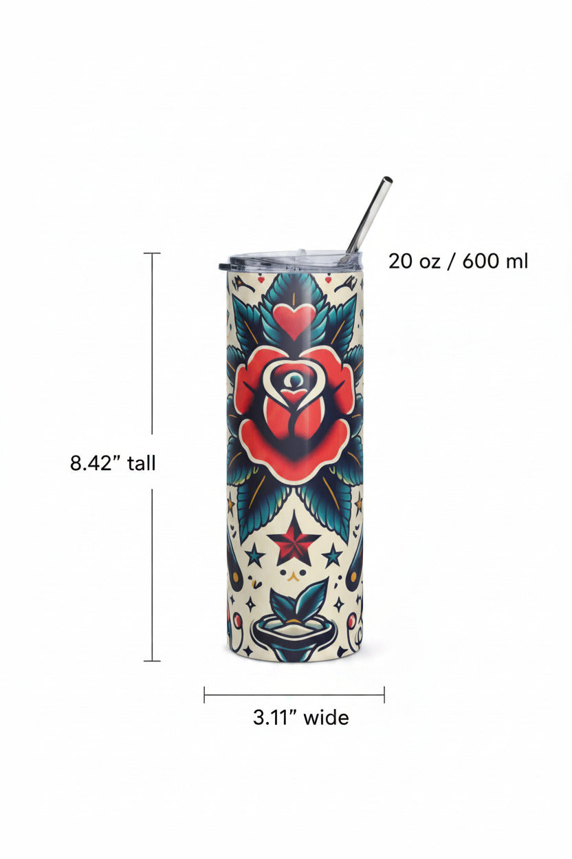 A tall, skinny tumbler with a clear lid and metal straw, decorated with a traditional tattoo-style floral design featuring a red rose, blue leaves, and stars on a cream background, set on a light marble surface.