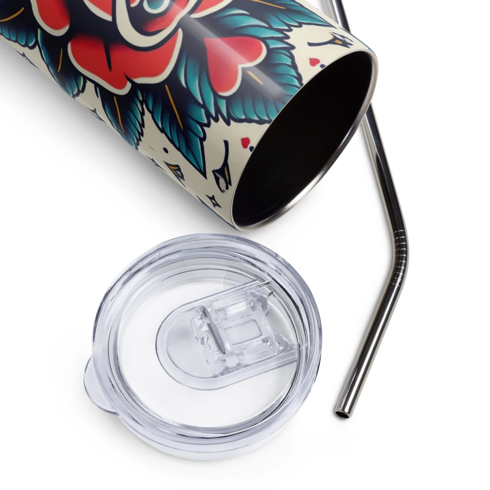 A stainless steel travel tumbler with a clear flip-top lid and metal straw, shown on a white background. The tumbler features a traditional tattoo-style floral design with red, blue, black, and white colors.