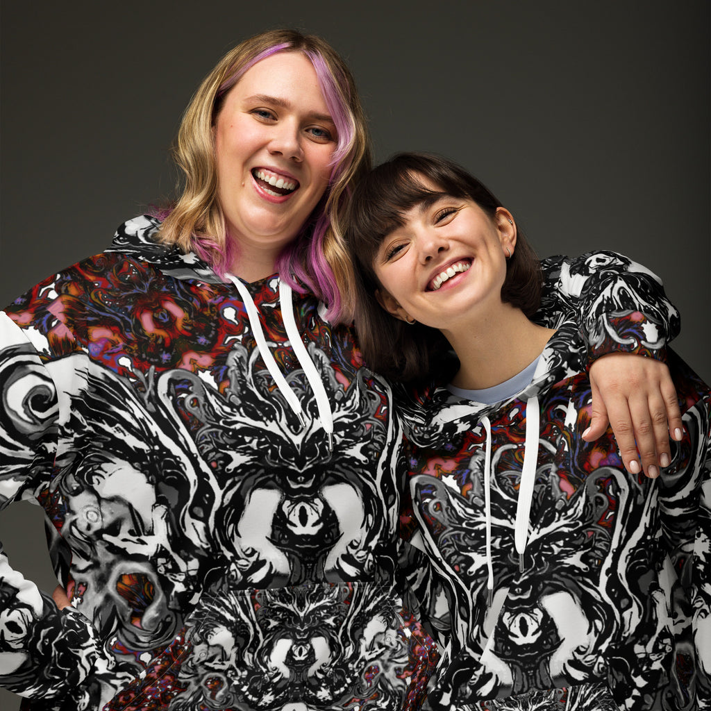 Two people wearing matching black and white patterned hoodies against a dark background