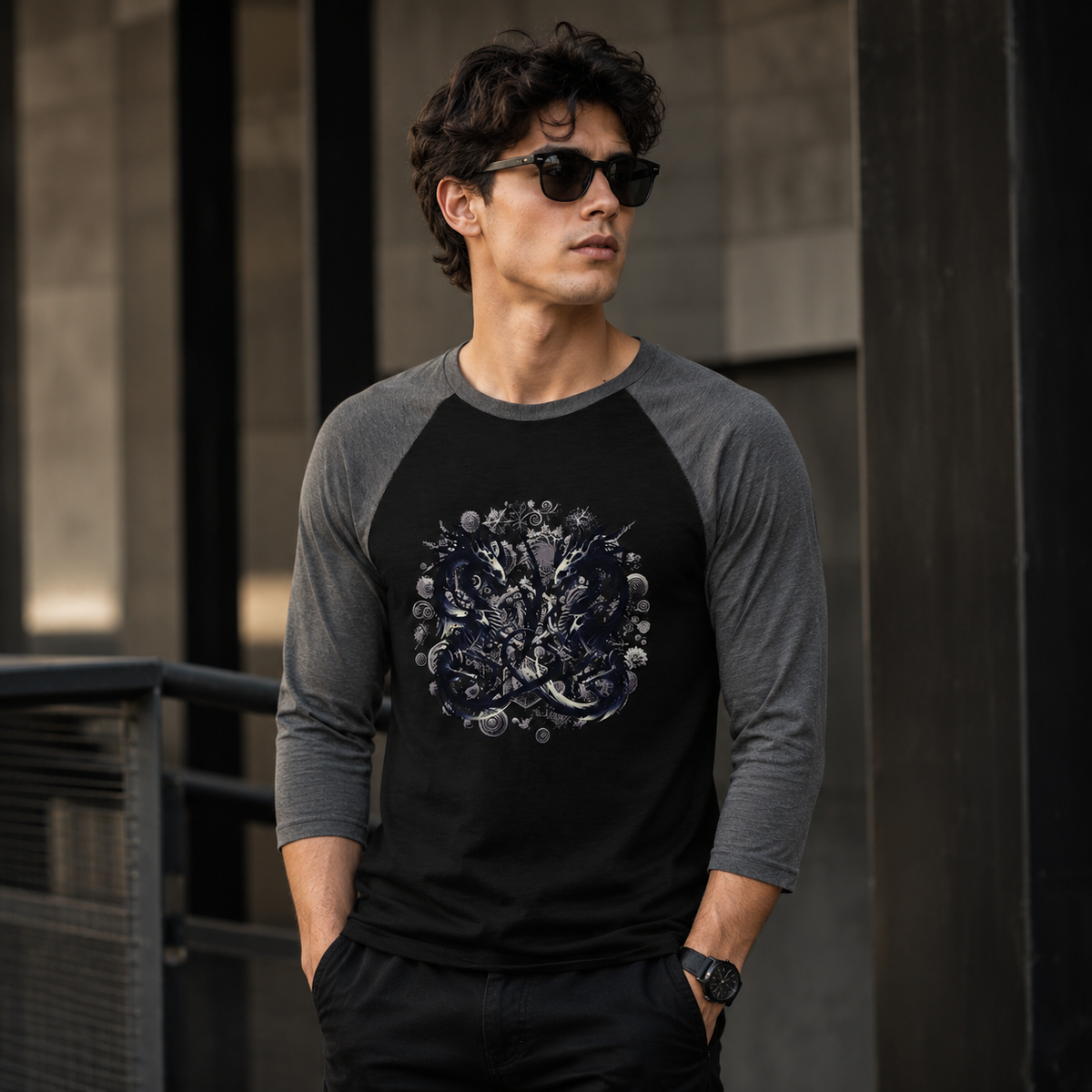 A man wearing a black and gray 3/4-sleeve raglan baseball t-shirt with a detailed graphic print on the chest, standing in an urban setting.
