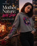 A woman wearing a gray cropped hoodie with a colorful floral wolf graphic on the chest and purple floral embroidery on the sleeve, posed outdoors at dusk with city lights and roses in the background. Text on the left reads 'HighDezign Mother Nature: Wild Side Raw Edge Crop Hoodie'.