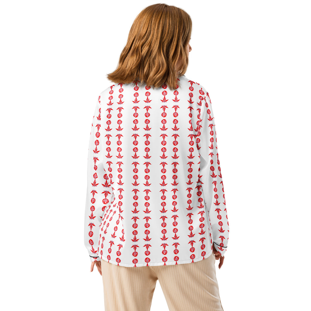 A woman wearing a long sleeve pajama top with a chest pocket and decorative piping detail. The top is white with a red anchor pattern.