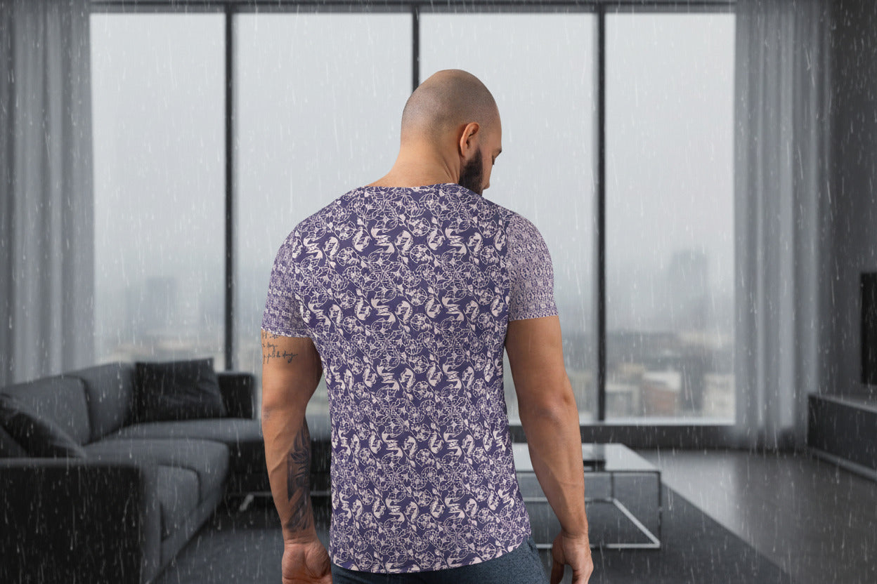 Man wearing a patterned shirt standing in a modern living room with large windows.