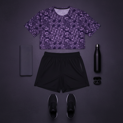 Purple patterned crop top, black shorts, black sneakers, black phone case, black water bottle, and black earbuds on a dark gray background.