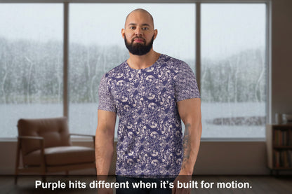 Man in a floral shirt standing in a bedroom holding a mug.