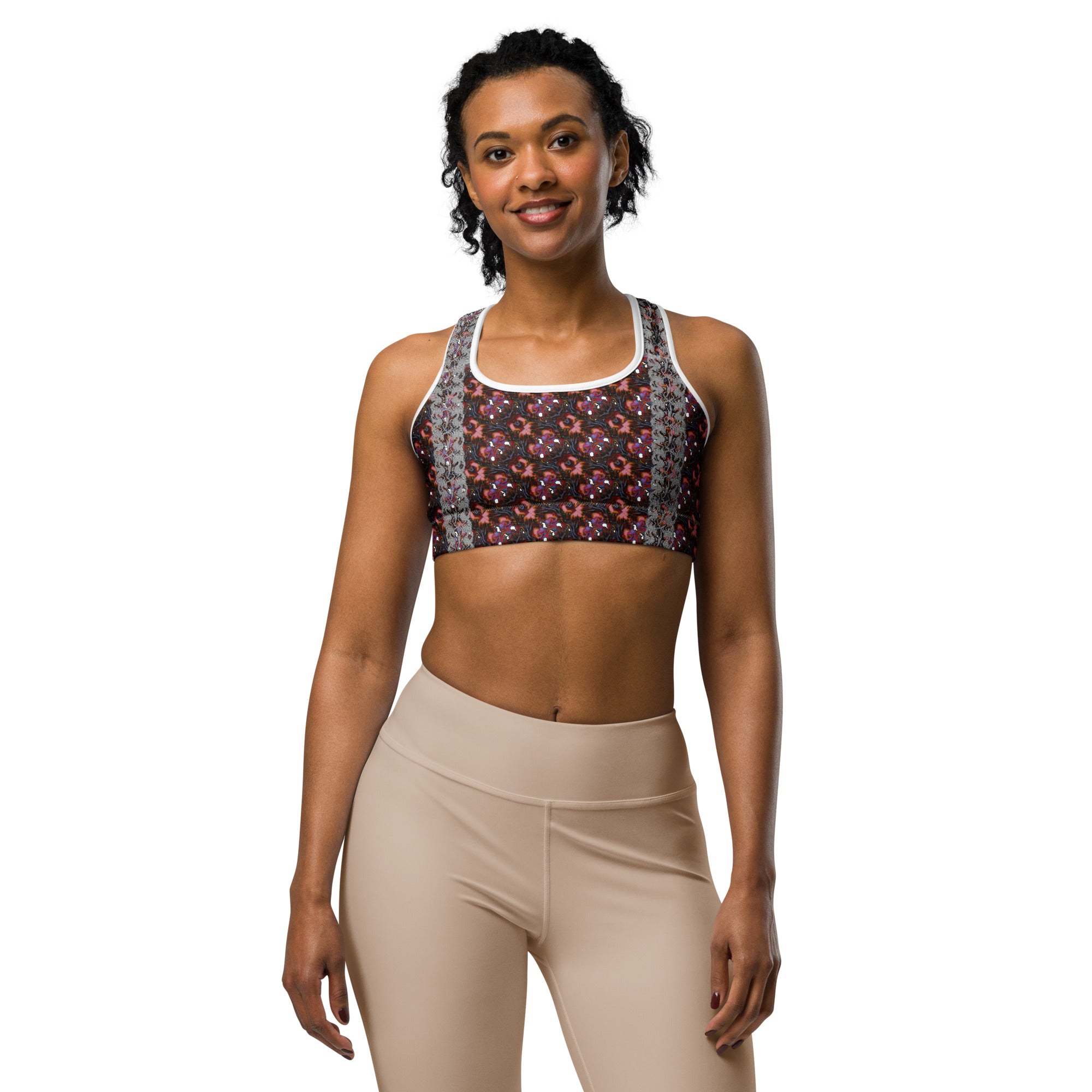 Woman wearing a colorful patterned sports bra and beige leggings on a white background