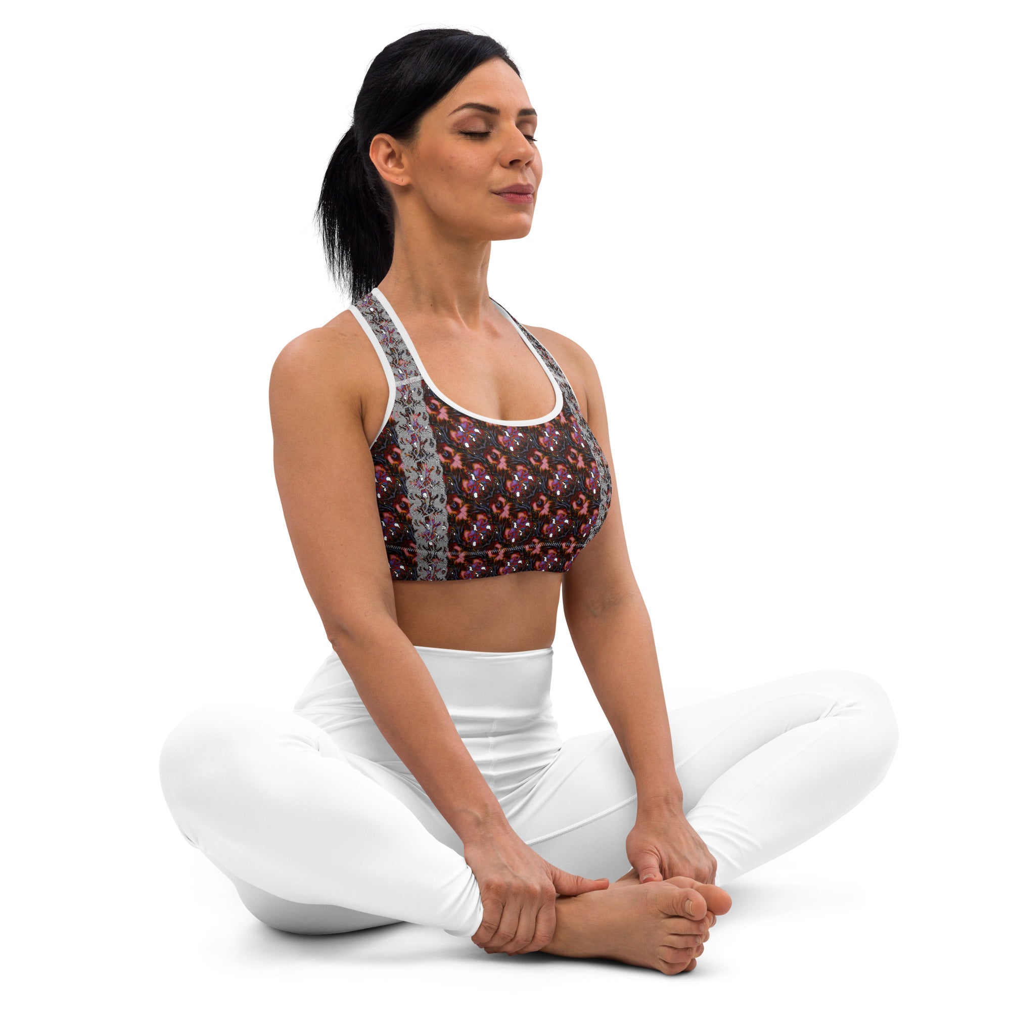 Woman in a yoga pose wearing a sports bra with a Halloween-themed design and white pants.